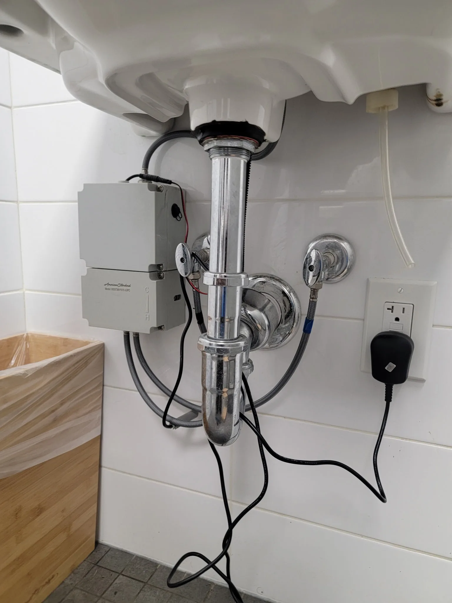 Leak detection sensor wired beneath a bathroom sink alongside the P-trap